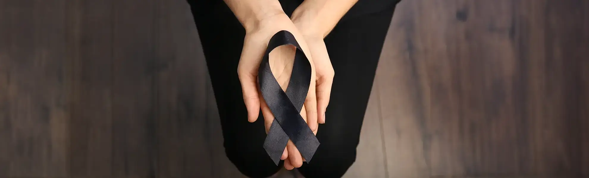 Junge Frau hält eine schwarze Trauerschleife in den Händen