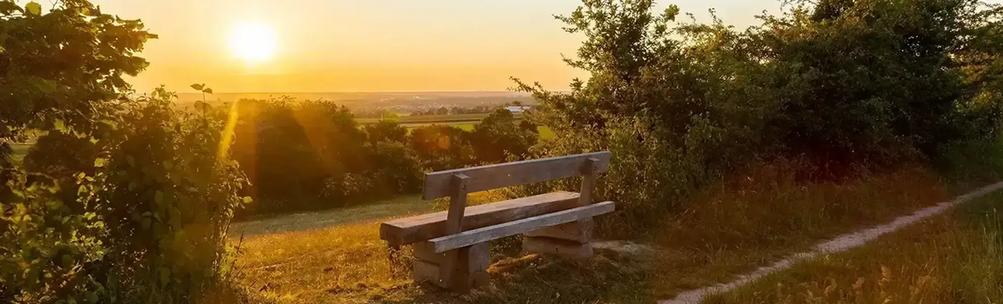Schöner Sonnenuntergang mit Blick in ein Tal mit einer schönen Holzsitzbank